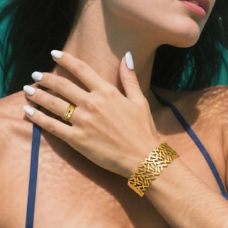 Gold bracelet and ring on a person's wrist with a blurred background
