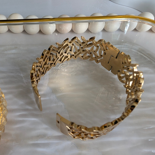 Gold bracelet with intricate design on a white surface