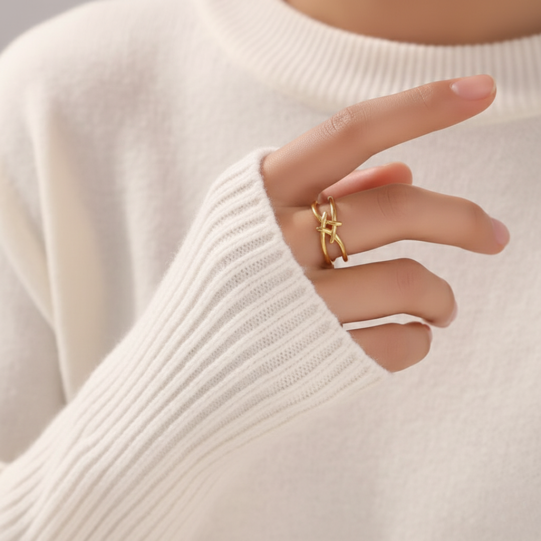 Gold ring on a person's finger against a neutral background