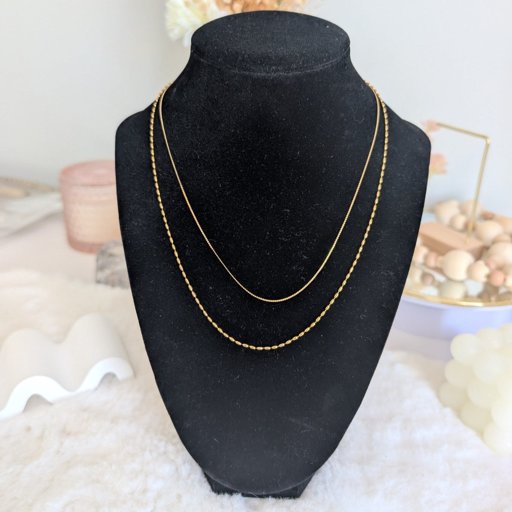 Gold necklace on a black velvet bust with a soft white background