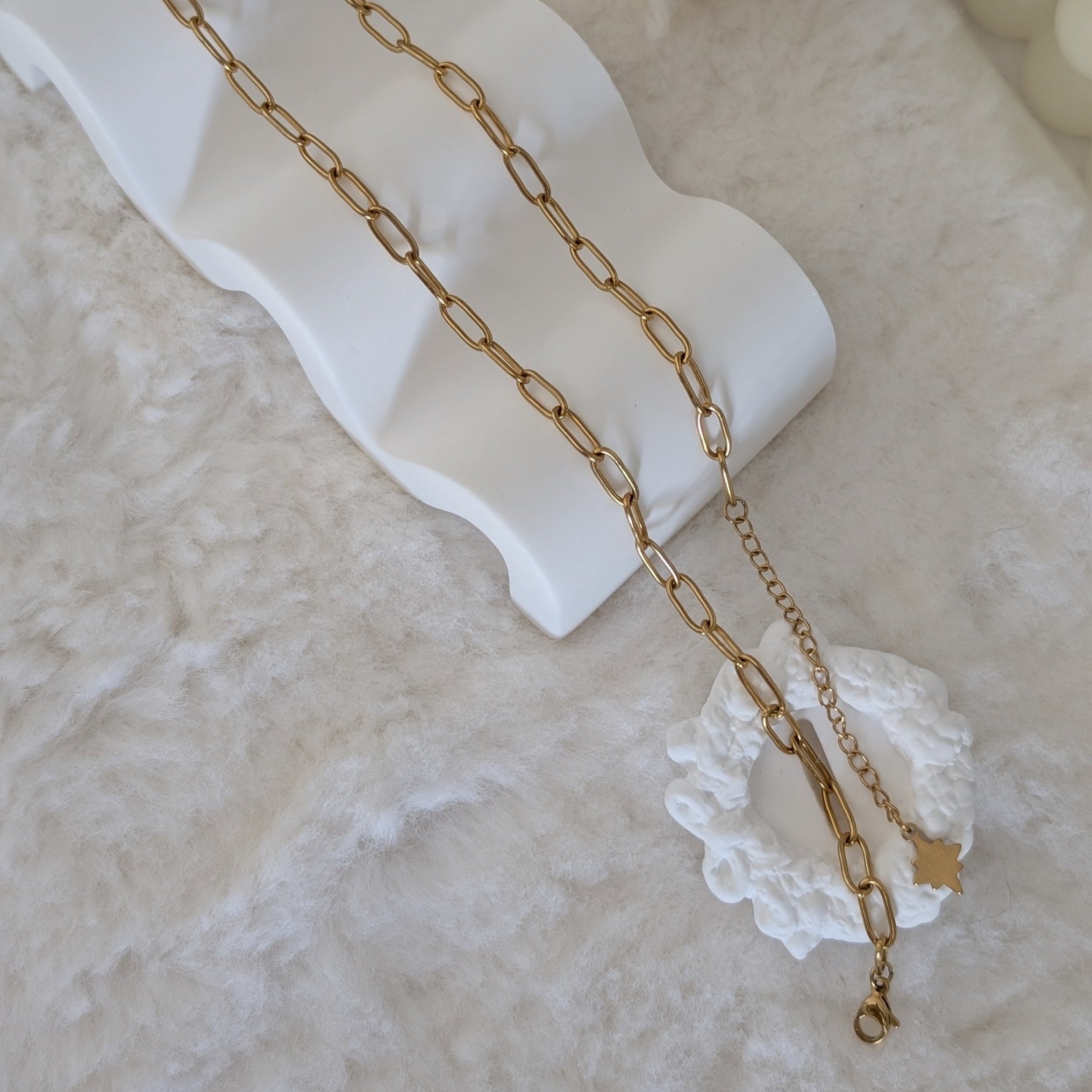 Gold chain necklace on a white dish with a soft, blurred background
