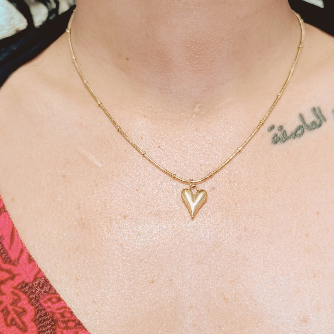 woman wears a gold-plated heart pendant necklace