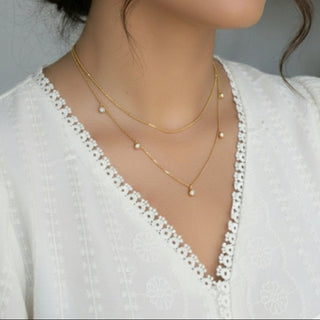 Woman wearing gold necklaces and earrings with a blurred background