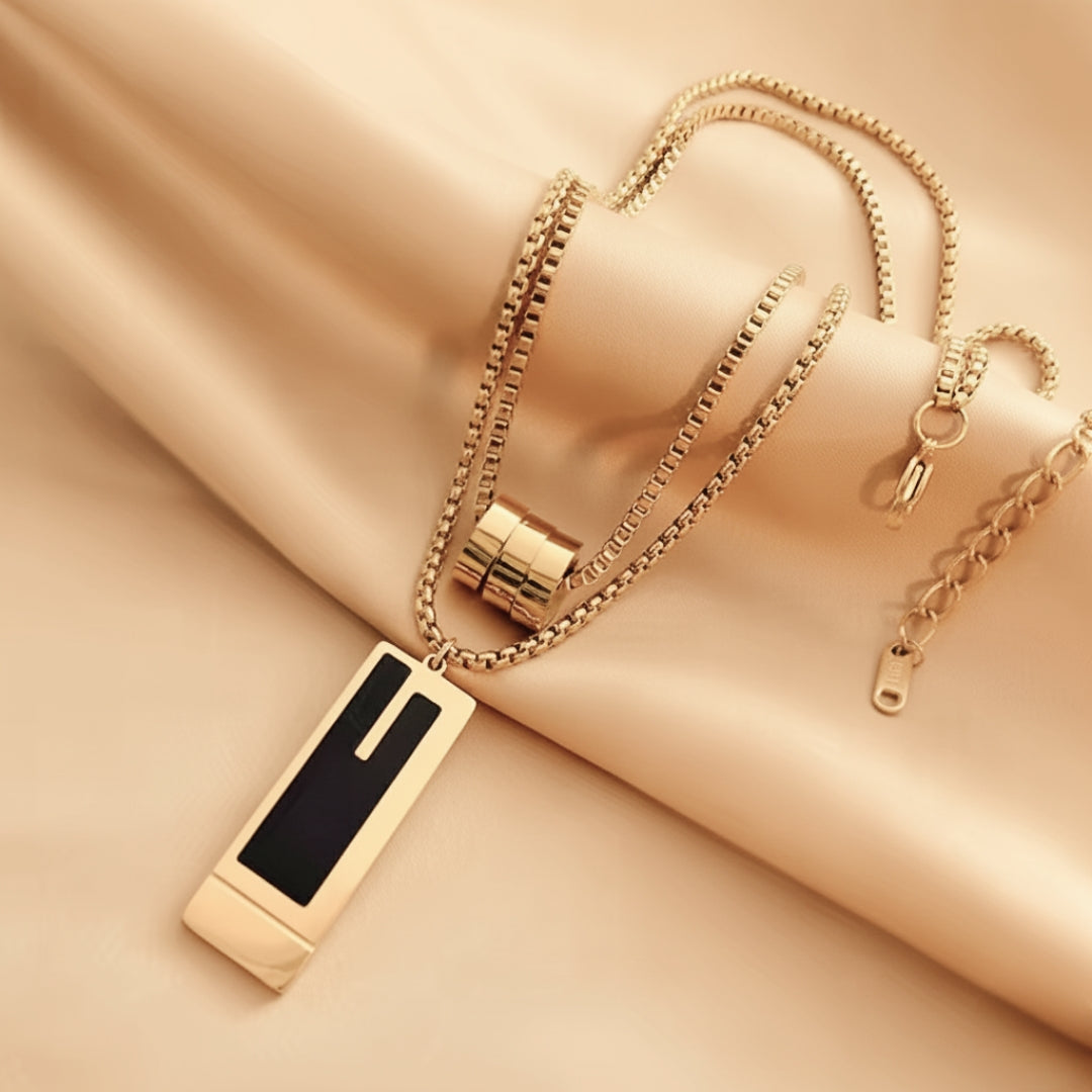 Gold necklace with a black pendant on a beige fabric background