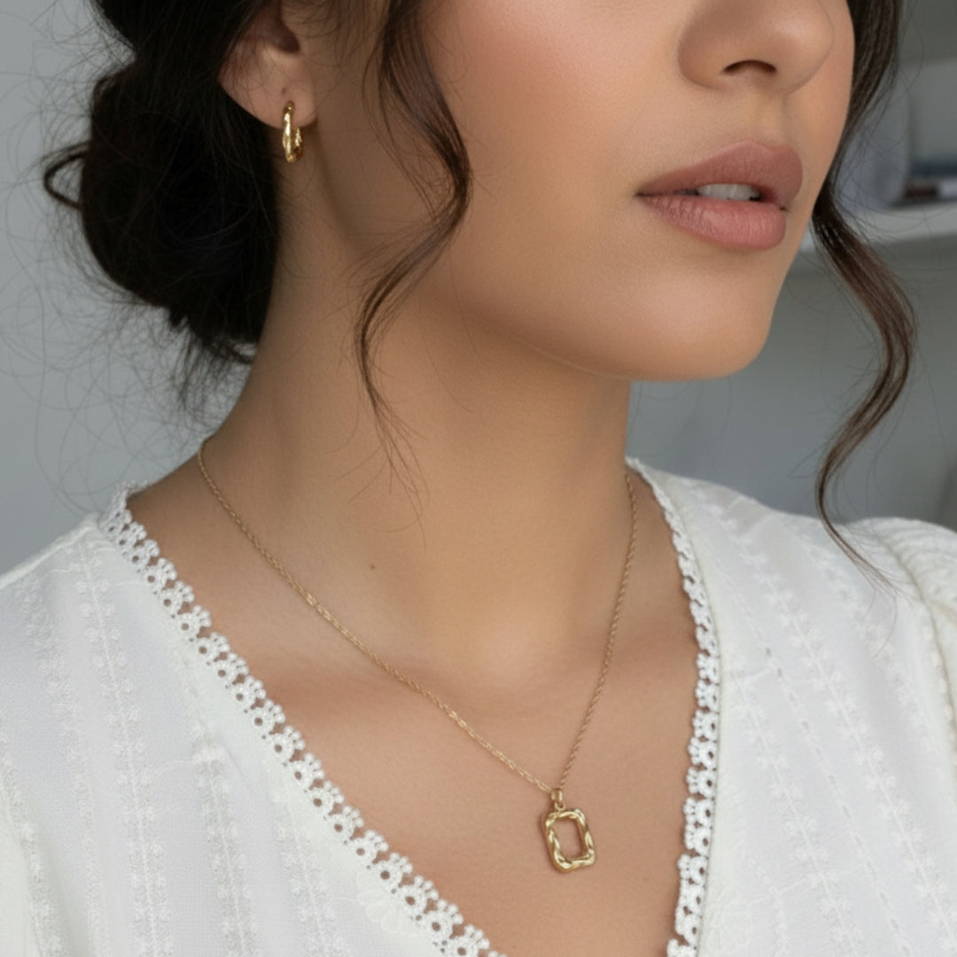 Close-up of a woman wearing a gold necklace and earrings with a blurred background