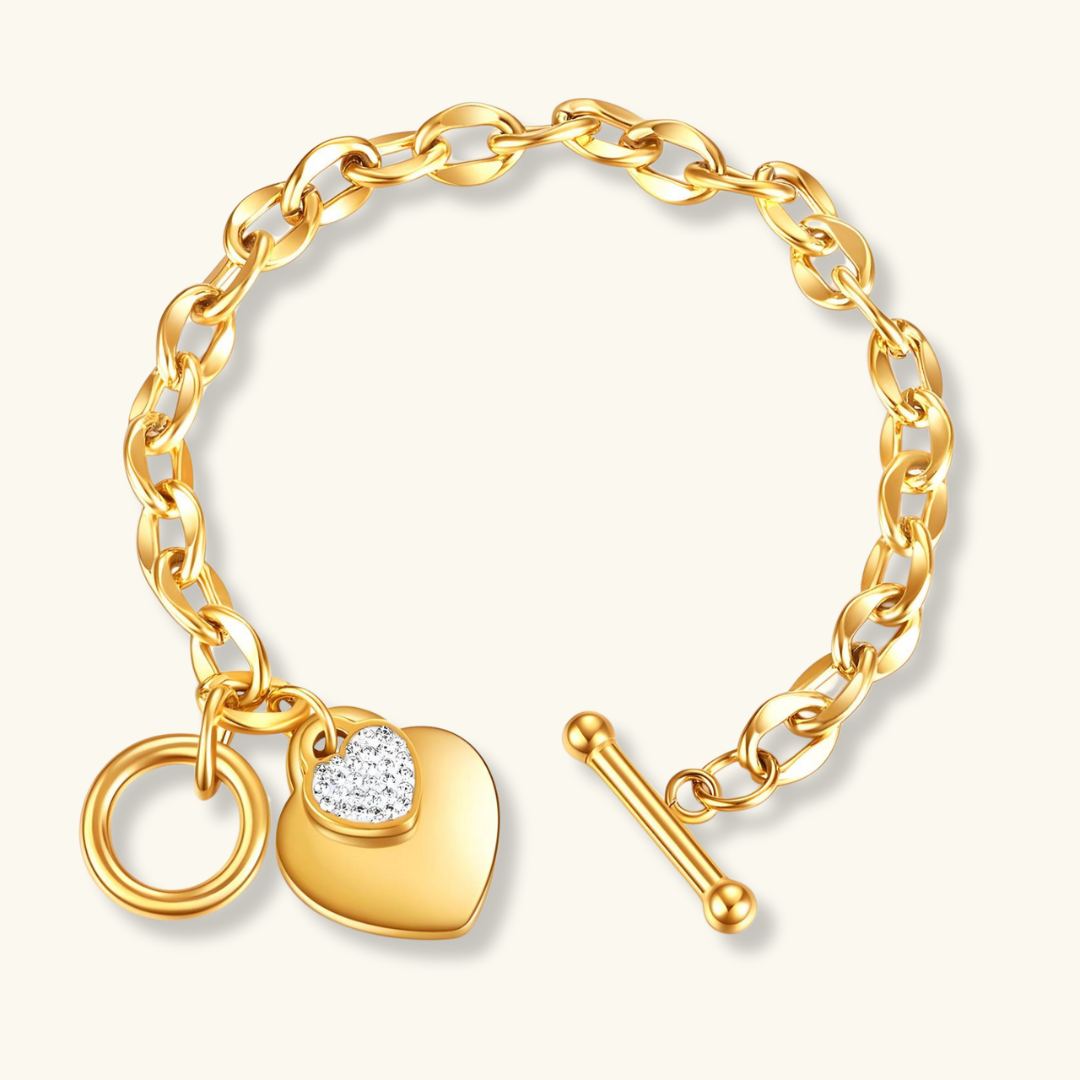 A gold-plated bracelet featuring two interlocking hearts with a cubic zirconia insert, fastened with a ring and bar clasp.
