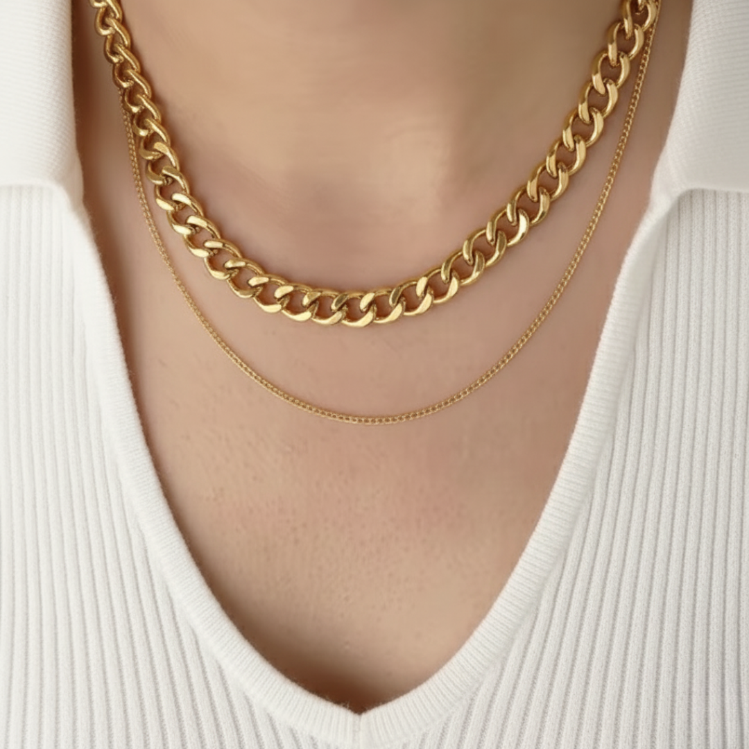 Two gold chain necklaces on a person wearing a white top.