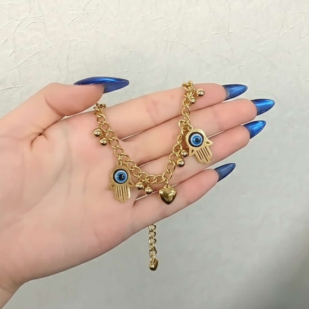 Gold bracelet with charms on a hand against a neutral background