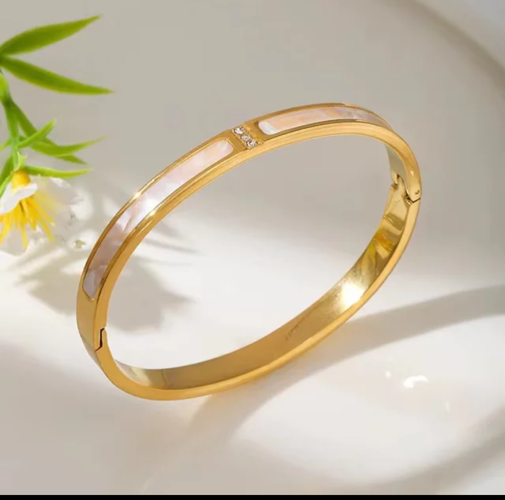 Gold bracelet with a pink interior on a light background