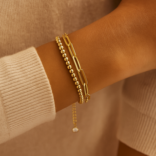 Gold bracelet on a wrist with a neutral background