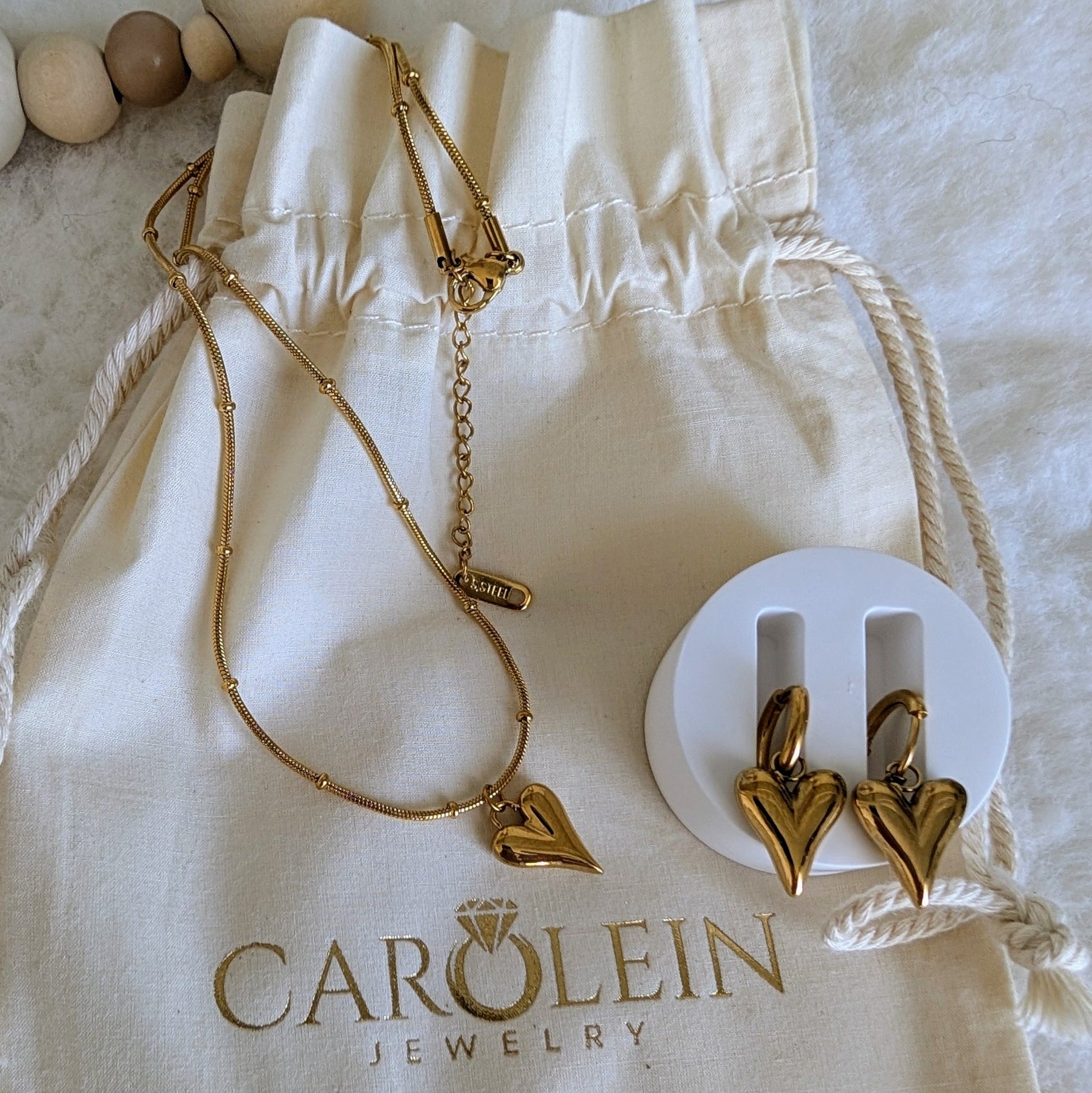 Gold necklace and earrings on a Carolein Jewelry pouch.
