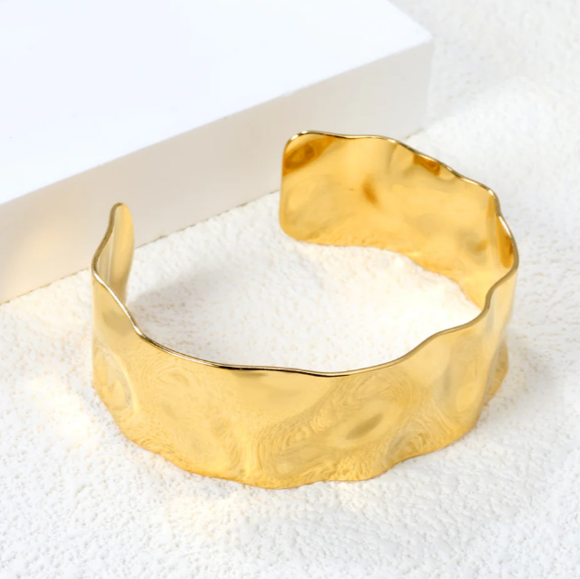 Gold BANGLE on a textured white surface