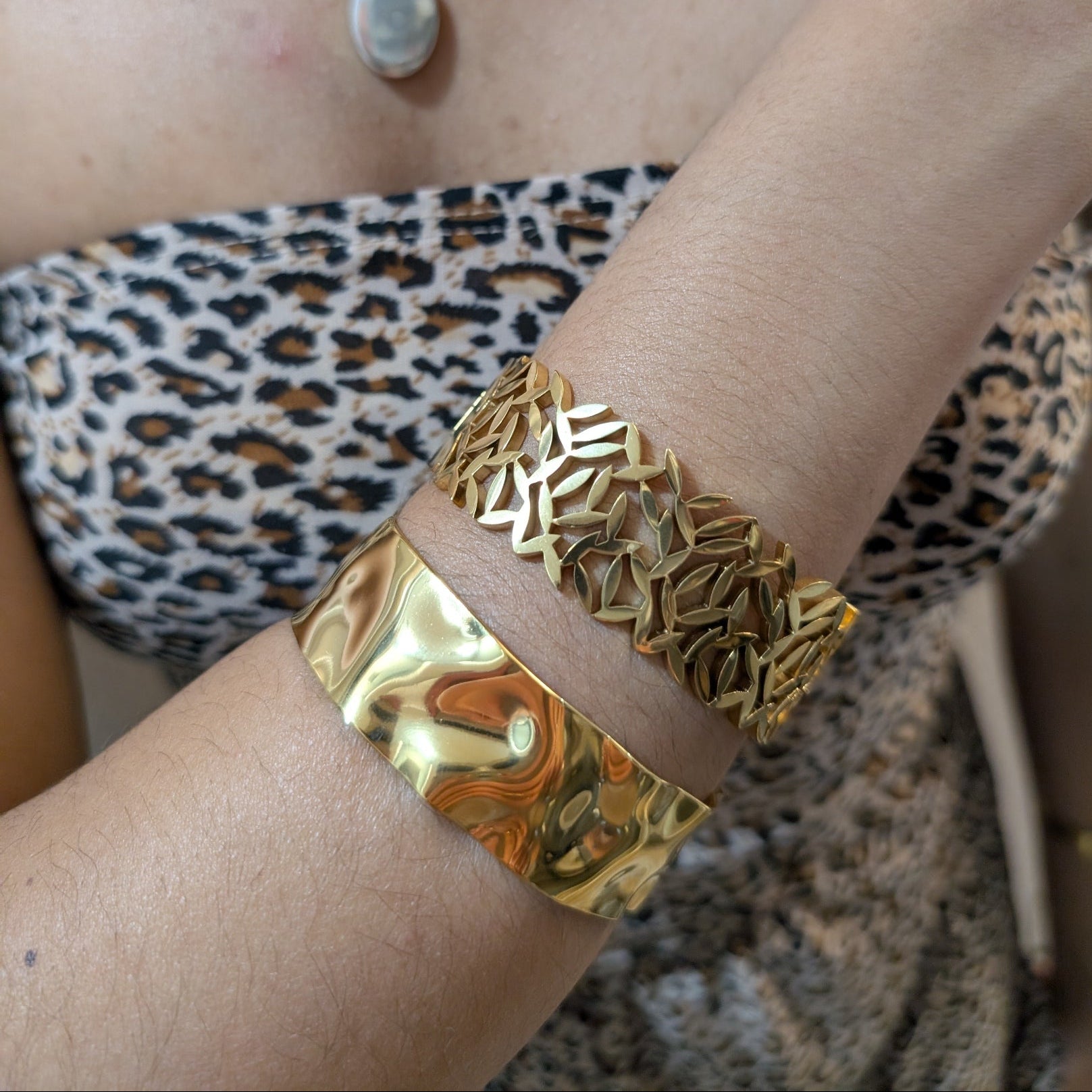 Gold bracelet on a wrist with leopard print top and necklace