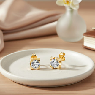 Gold earrings with clear gemstones on a white plate, blurred background