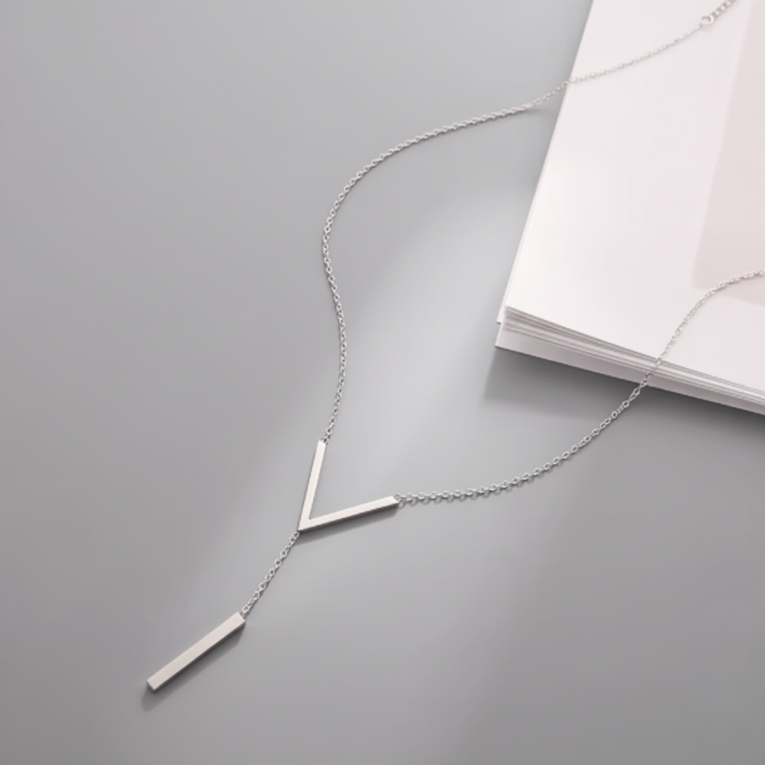 Silver necklace with three vertical bars on a gray surface