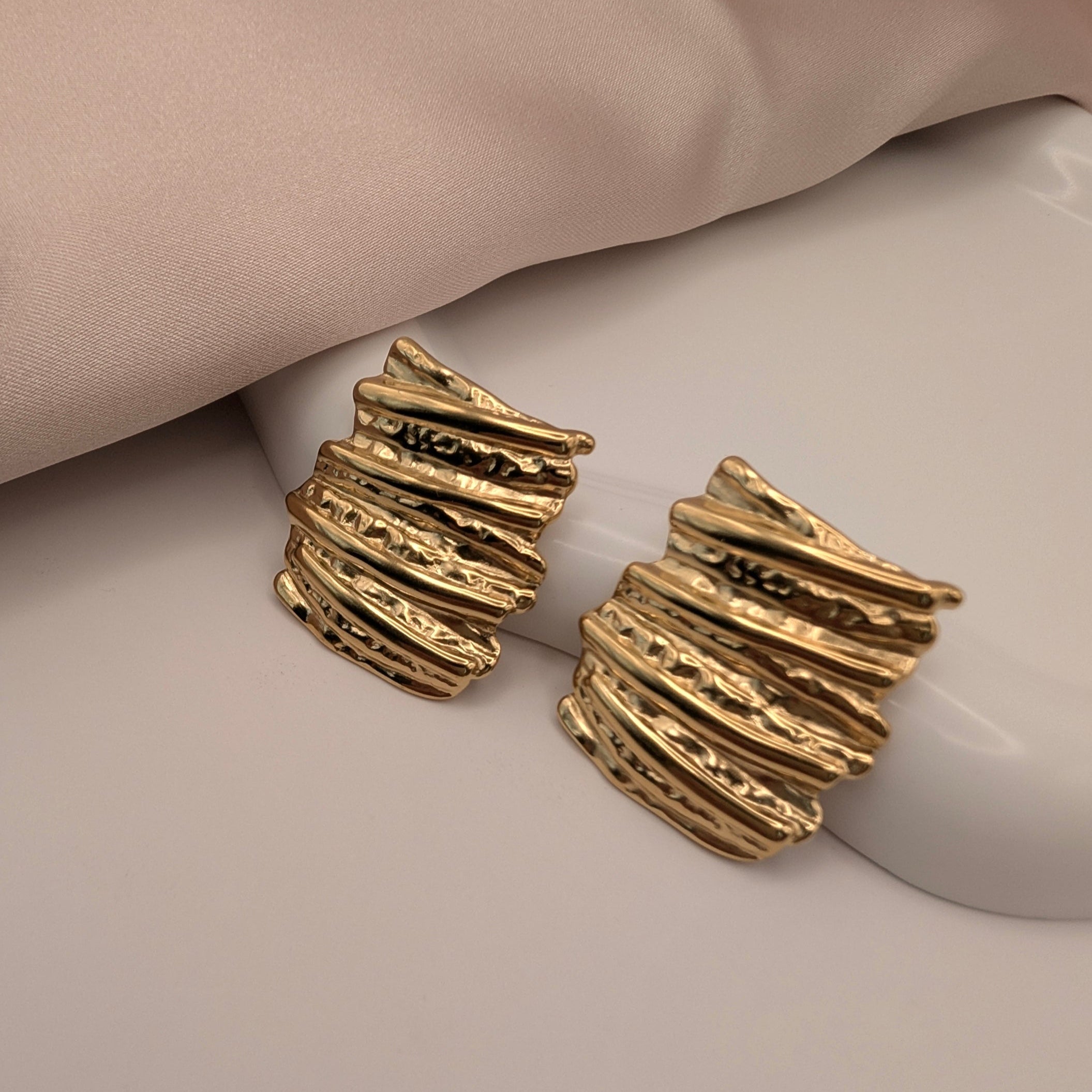 Gold textured earrings on a mannequin