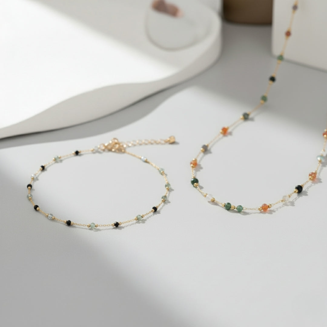Two delicate beaded bracelet and necklace on a light gray surface