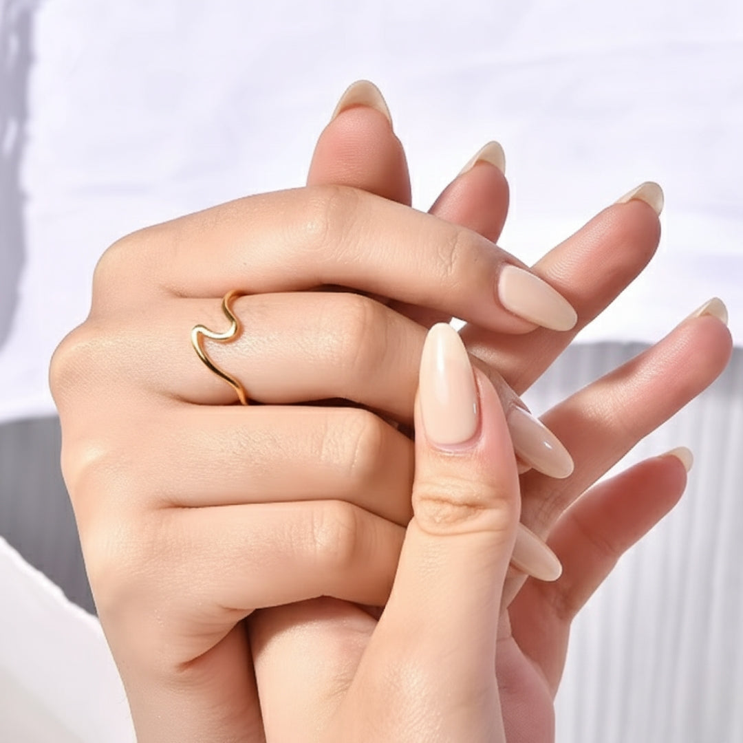 Close-up of a hand wearing a gold ring with a plain background