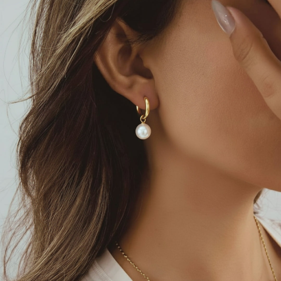 Close-up of a woman wearing a pearl earring with a neutral background