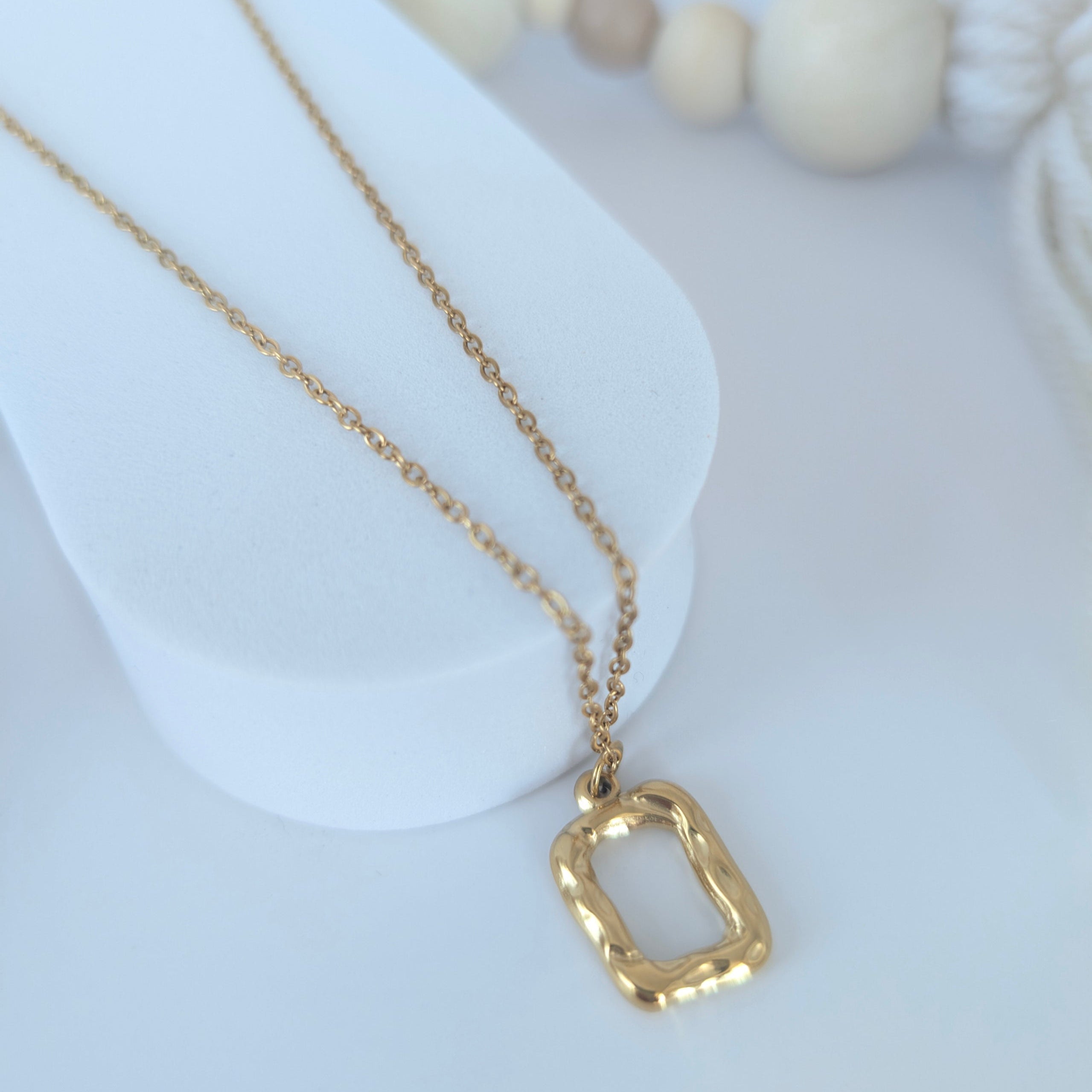 Gold necklace with a unique pendant on a white surface