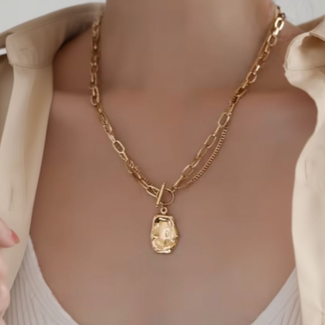 Gold chain necklace with a pendant on a neutral background