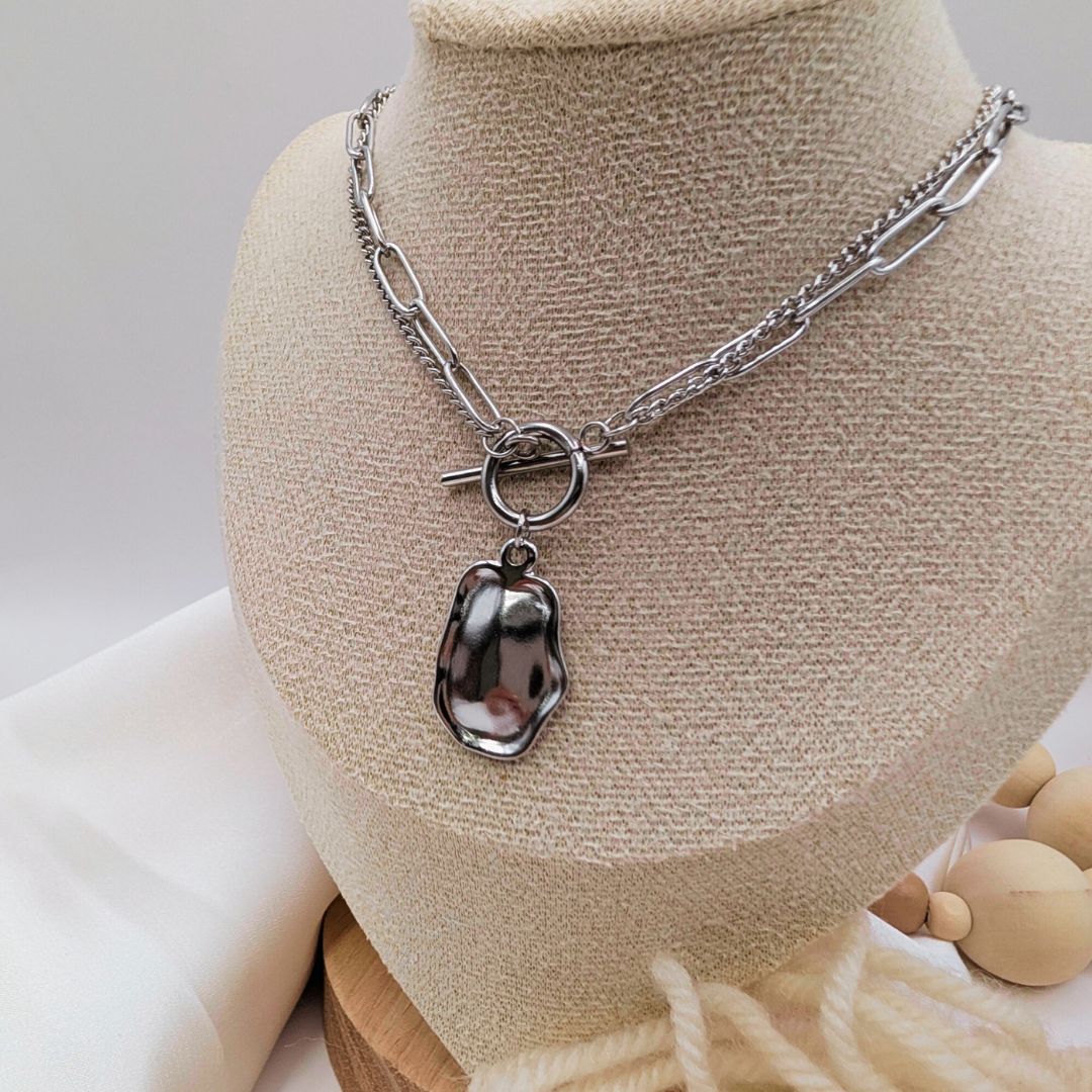 Silver necklace with a pendant on a mannequin bust.