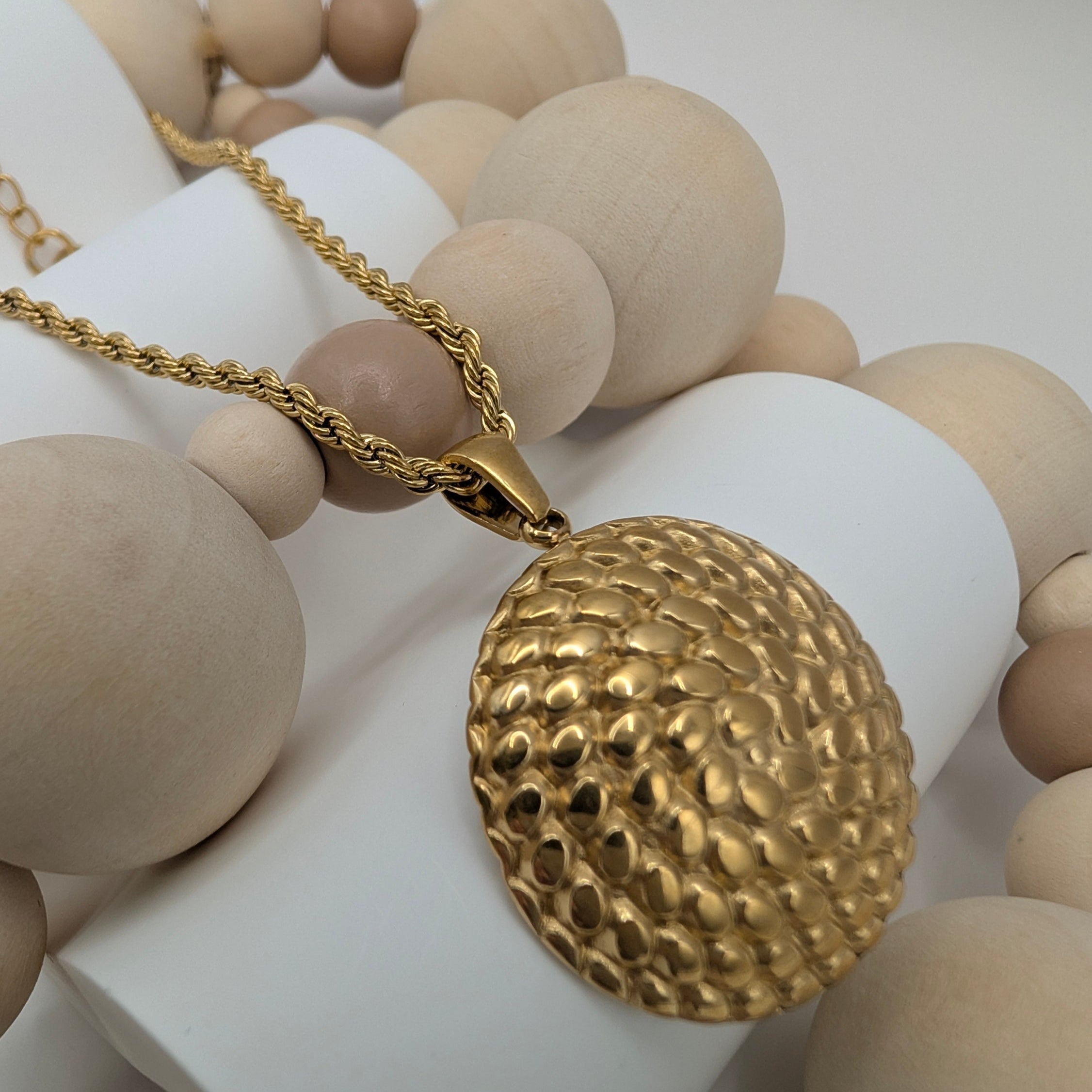 Gold necklace with a textured pendant on wooden beads