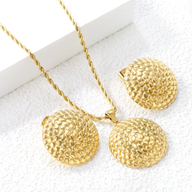 Gold necklace and earrings set on a white surface