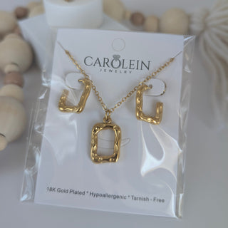 Gold necklace on a Carolein Jewelry card with decorative items in the background