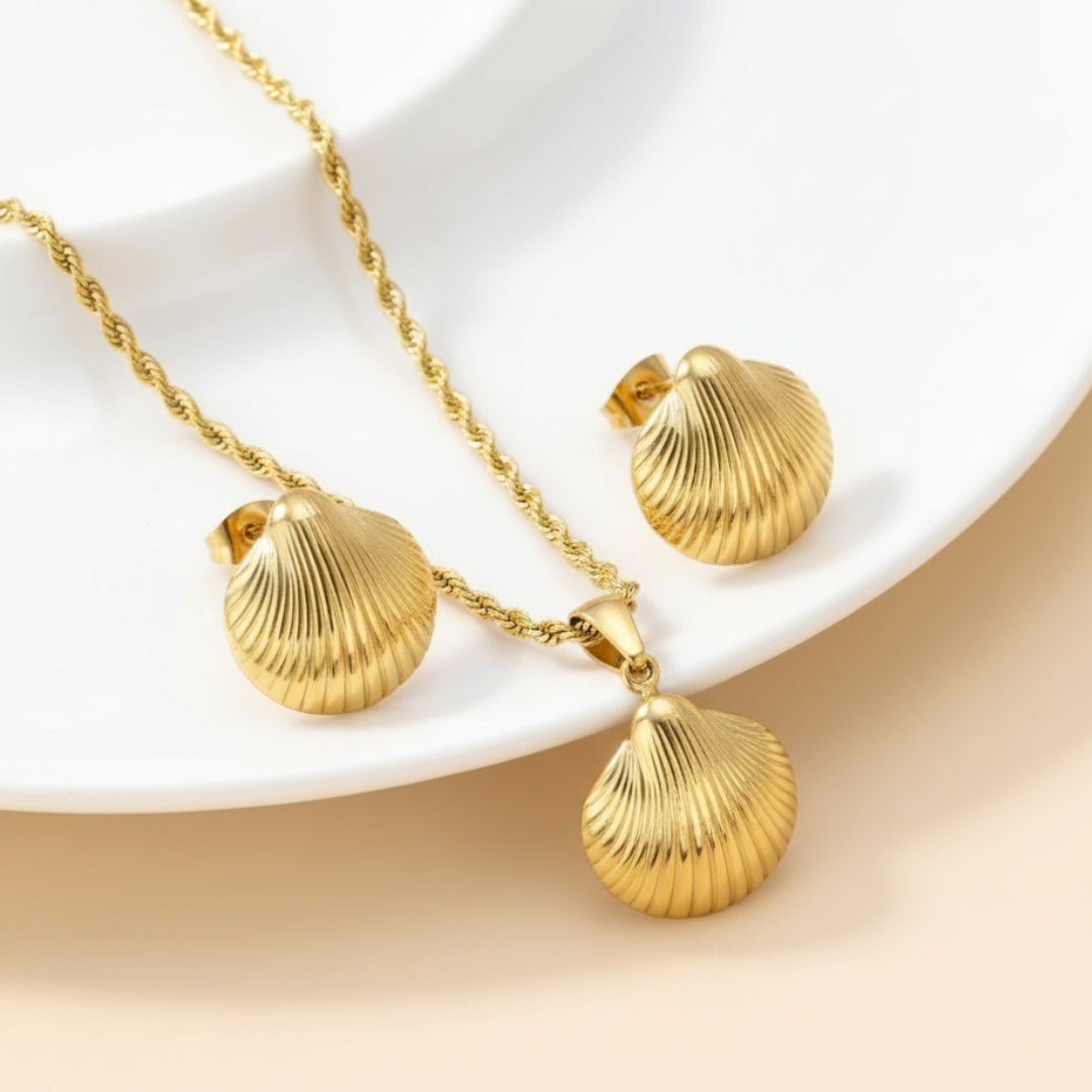 Gold shell necklace and earrings on a white plate with a beige background