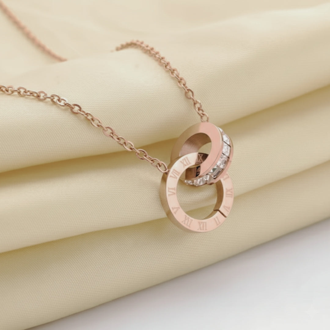 Rose gold necklace with interlocking rings on a beige fabric background