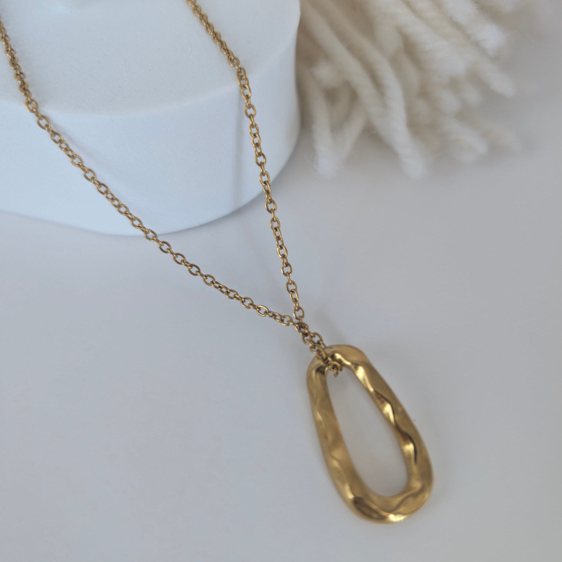 Gold necklace with a unique pendant on a white background