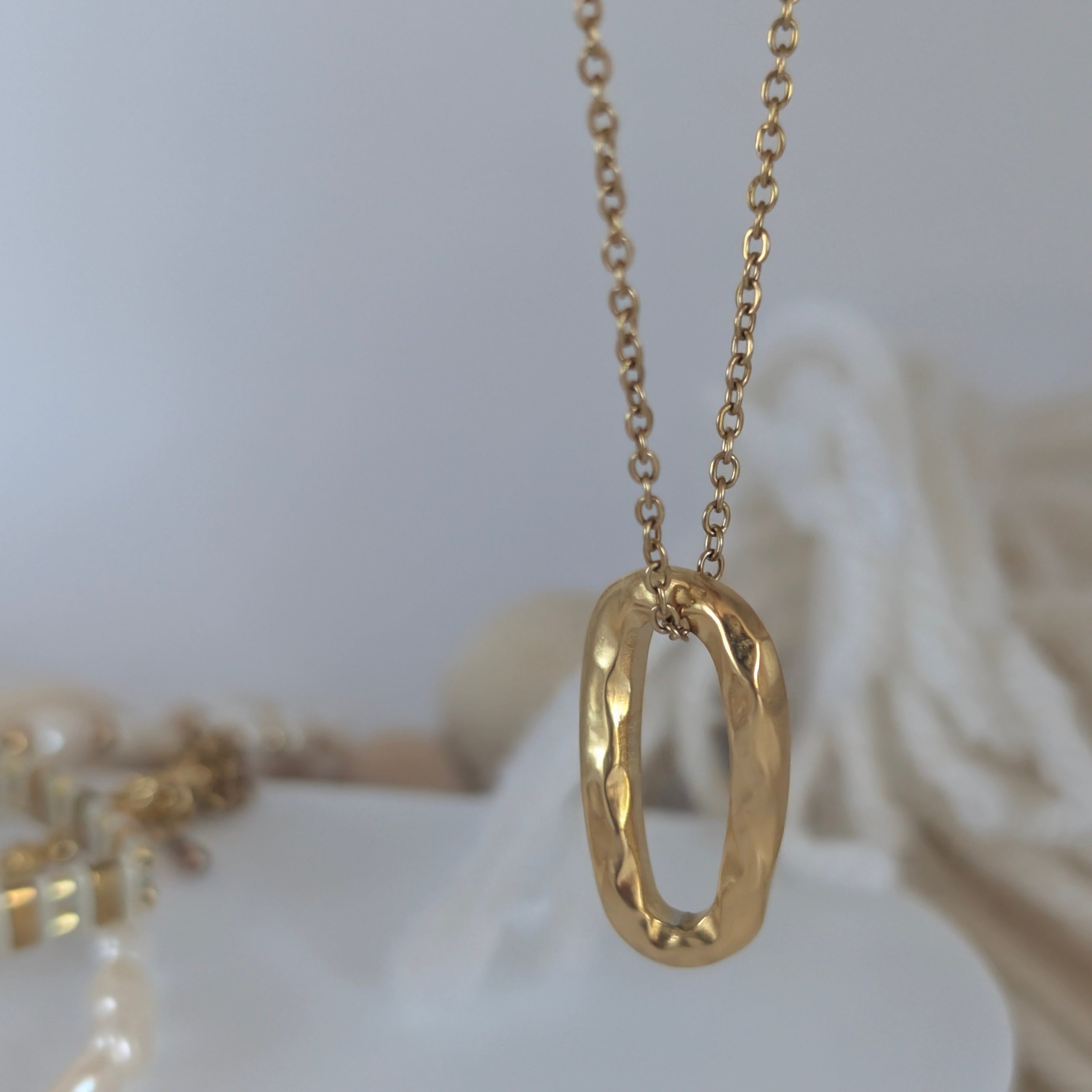 Gold necklace with a unique pendant on a white surface