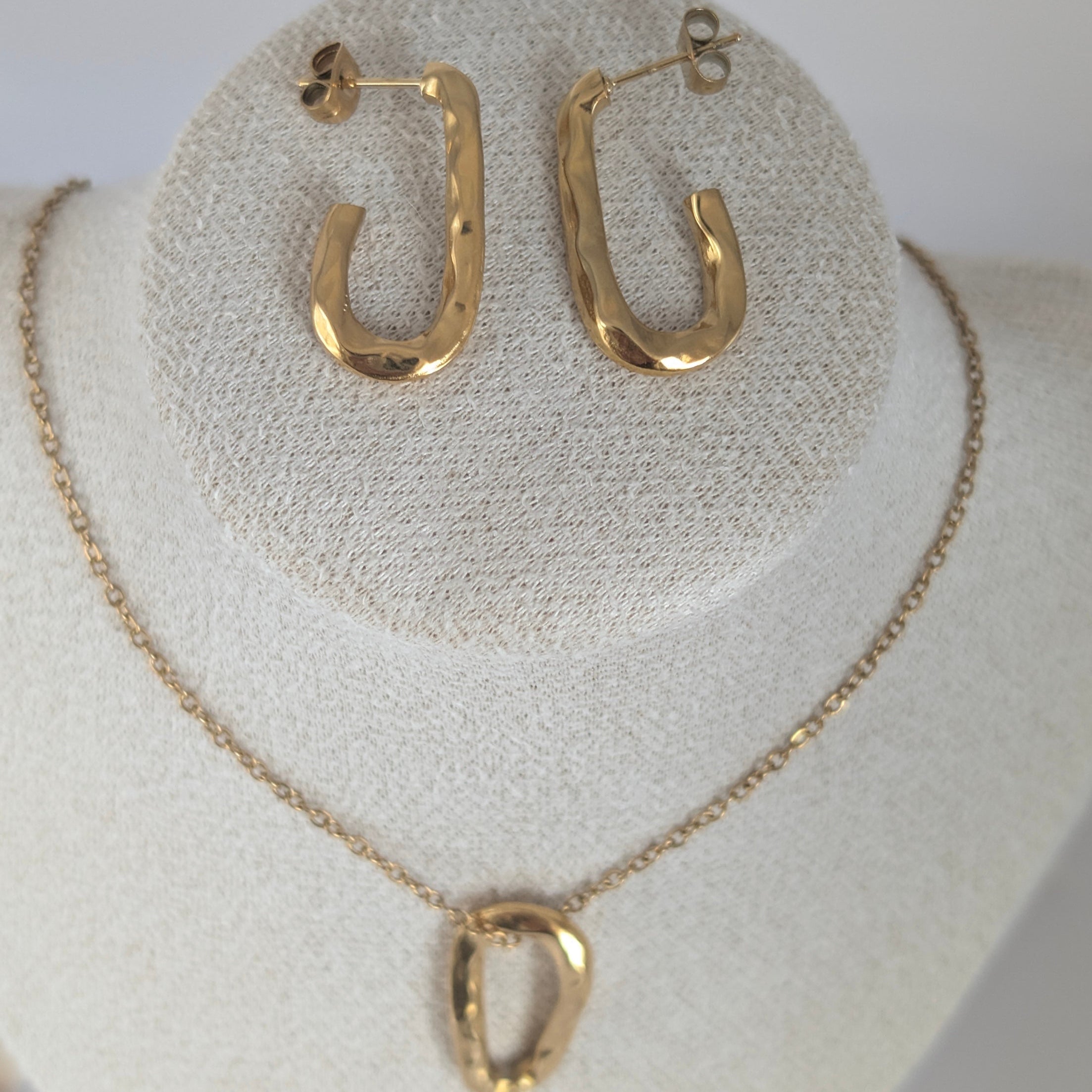 Gold hoop earrings and necklace set on a white stand