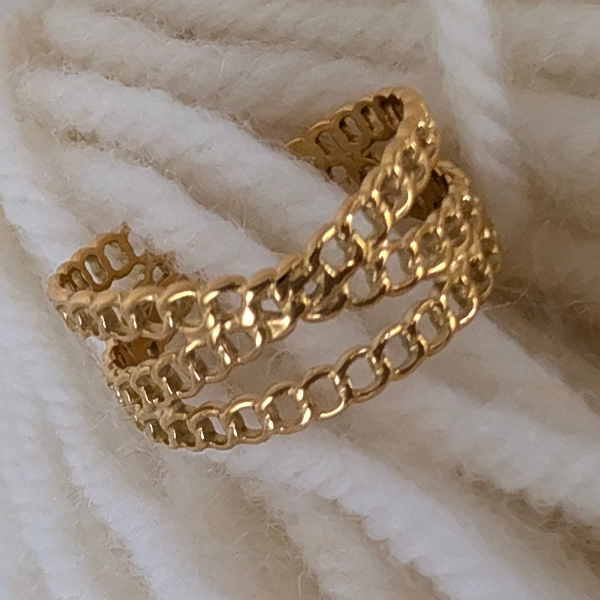 Gold chain bracelet on a textured white surface