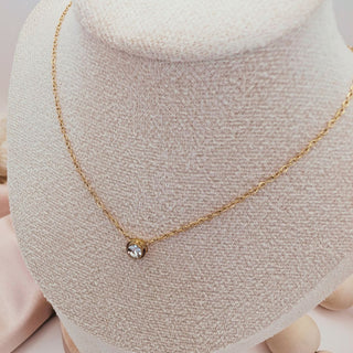 Gold necklace with a small pendant on a mannequin bust.