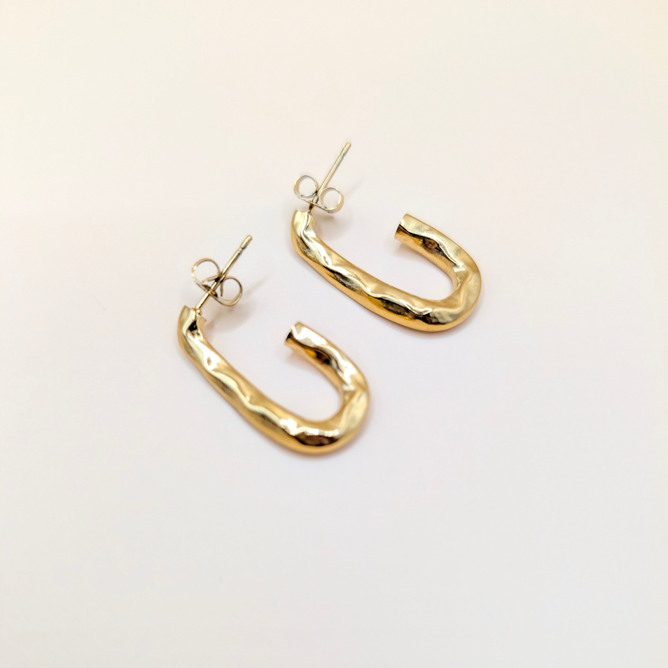 Gold hoop earrings on a light beige background