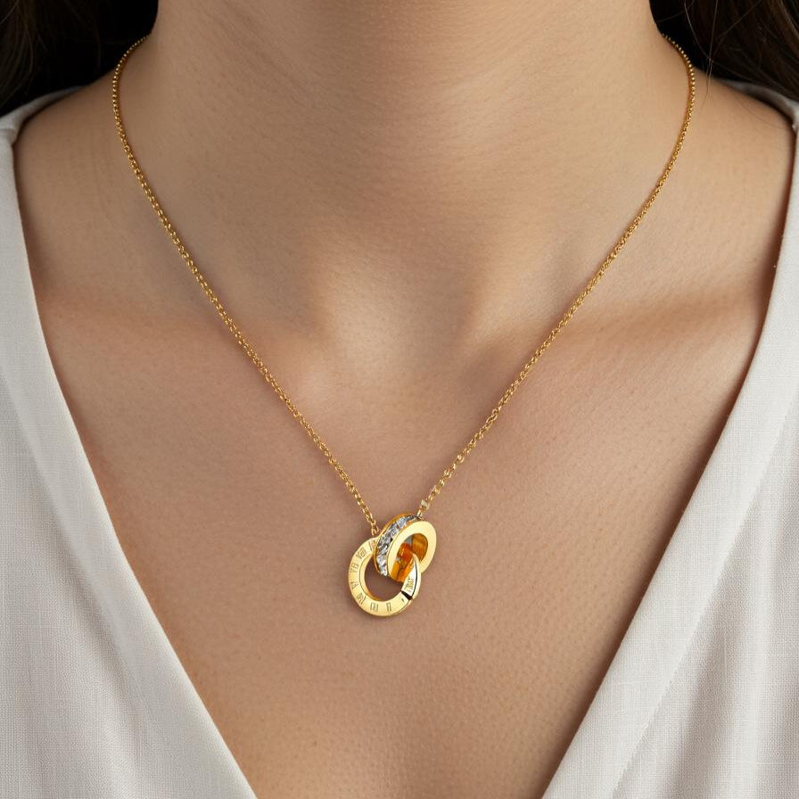 Gold necklace with a pendant worn by a person in a white top