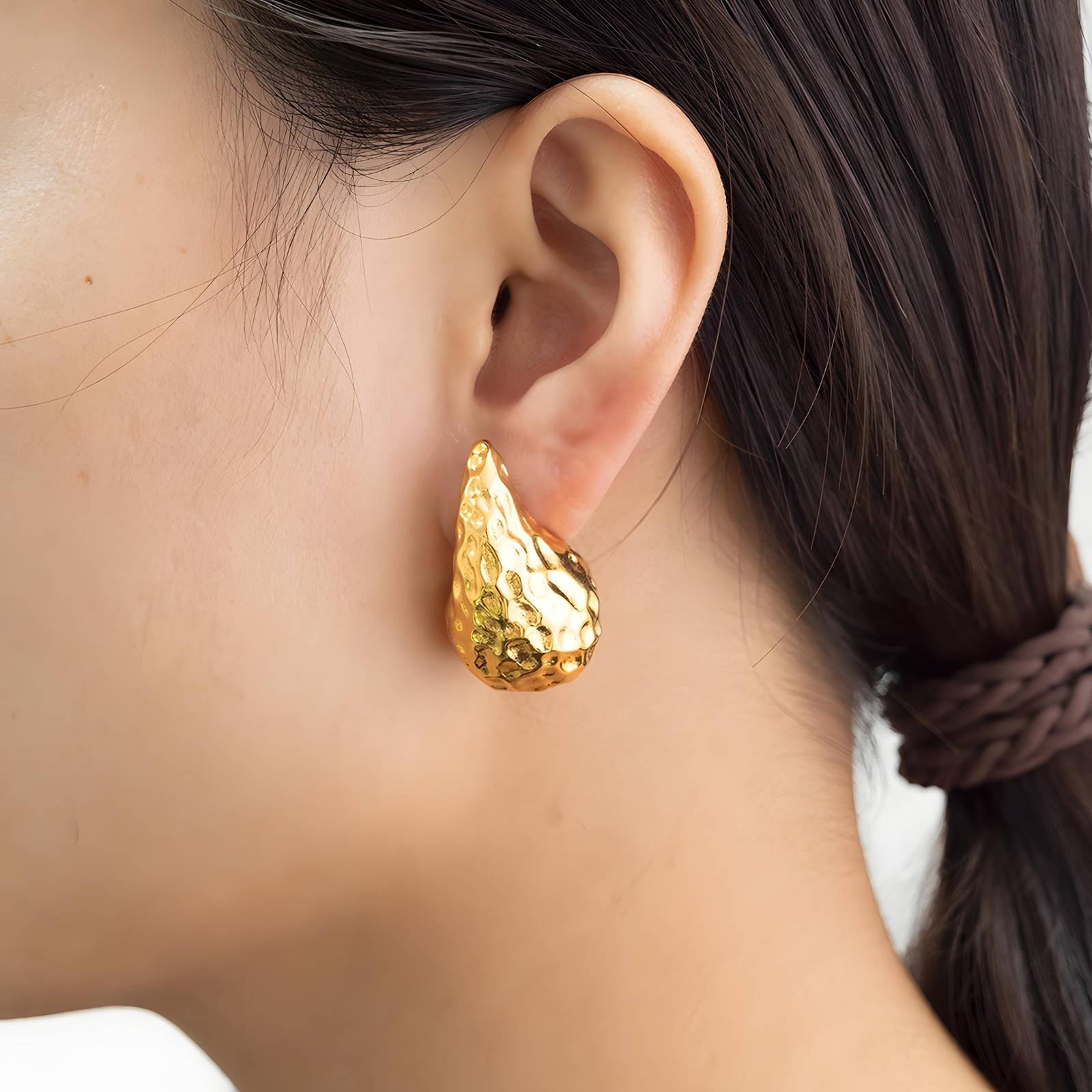 Gold earring worn by a person with a blurred background