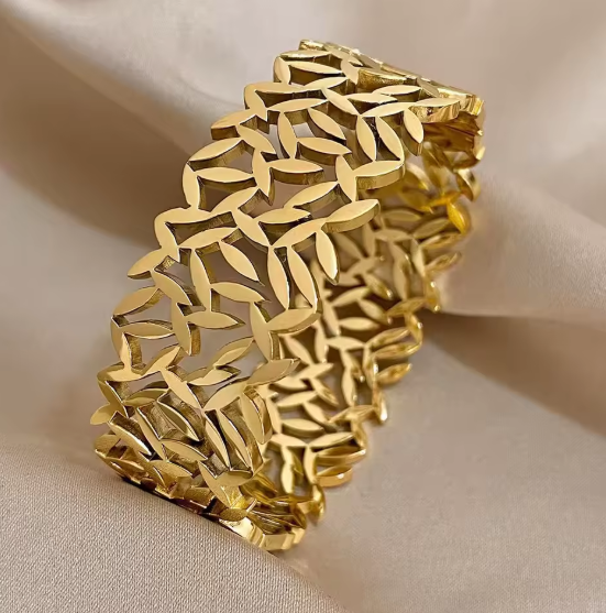 Gold bracelet with leaf-like pattern on a beige background