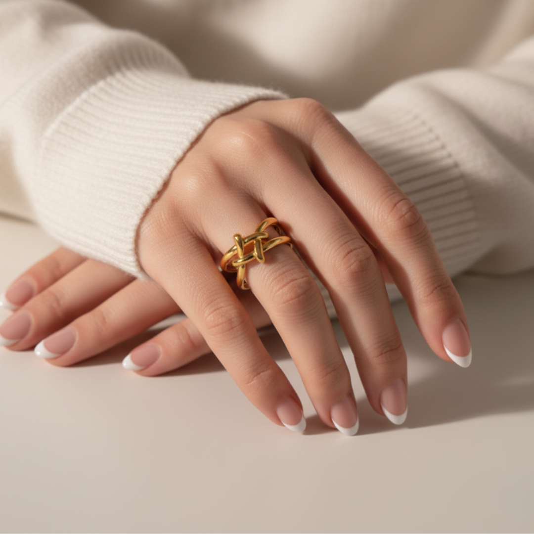 Hand wearing a gold ring on a neutral background