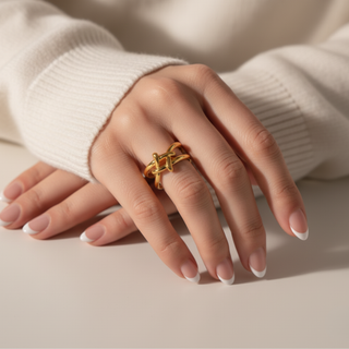 Hand wearing a gold ring on a neutral background