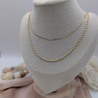 Gold chain necklace on a mannequin bust with a neutral background