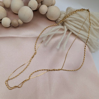 Gold chain necklace on a soft pink fabric background