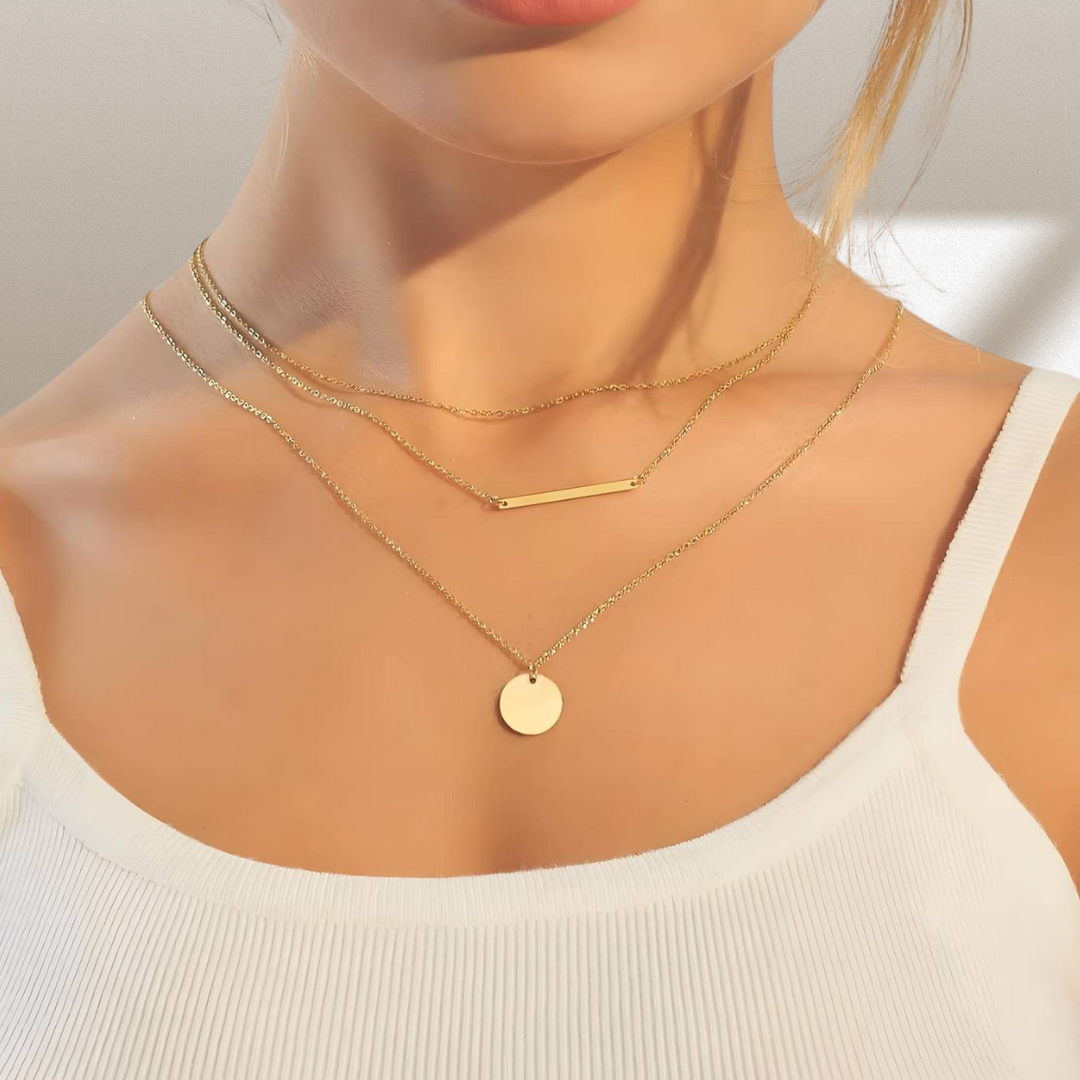 Gold necklaces on a mannequin with a neutral background