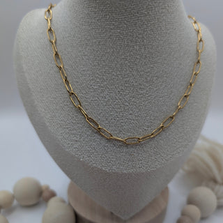 Gold chain necklace on a gray bust with wooden beads on a white background