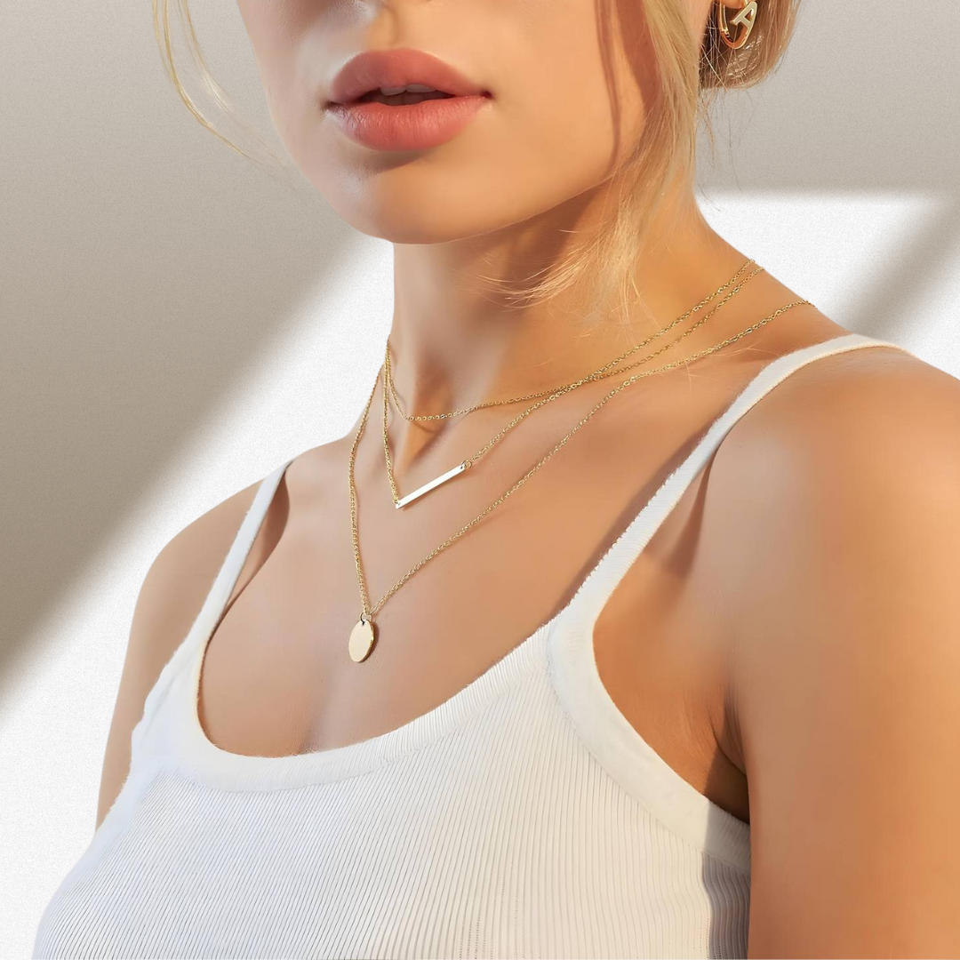 Woman wearing gold necklaces and earrings with a neutral background