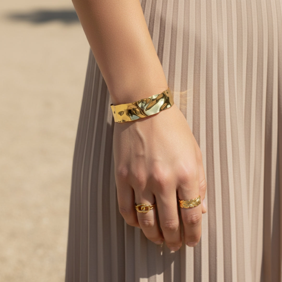 Gold  bangle and rings on a hand with a neutral background