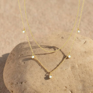 Gold necklace with small gemstones on a stone surface