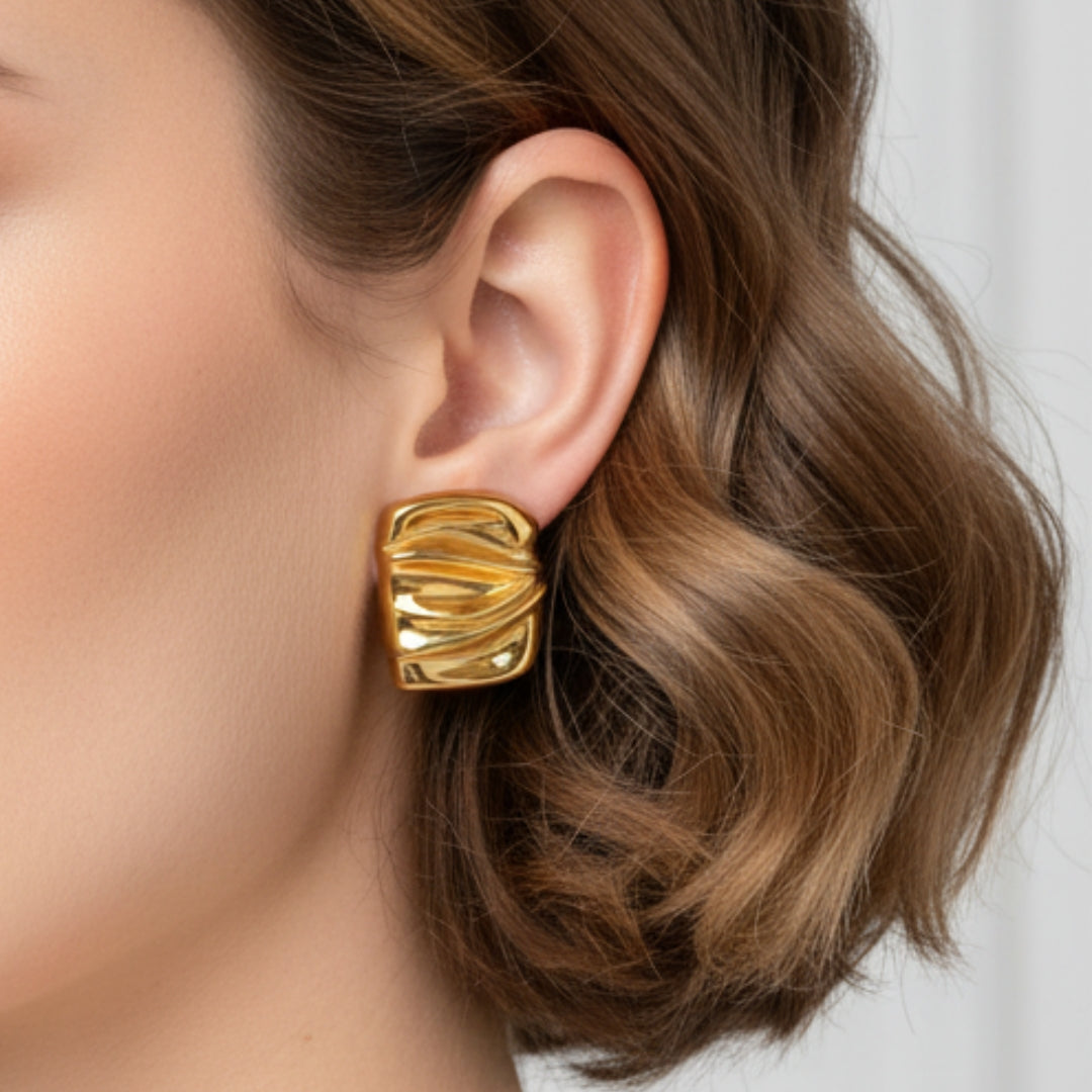 Gold earring worn by a person with wavy hair